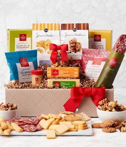 A Thanksgiving gift basket with a red bow filled with a variety of gourmet foods