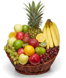 Christmas fruit basket with fresh apples, pears and holiday treats in a woven basket