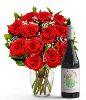 A dozen red valentines day roses with a bottle of red wine