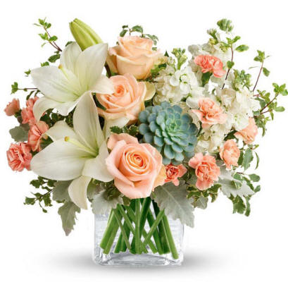 Peach colored roses and lilies in a clear vase